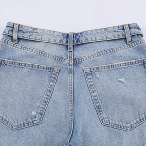 Détail de jeans en denim bleu clair montrant les poches arrière et l'aspect usé