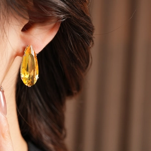 Close-up of yellow teardrop zircon earrings with silver setting on elegant model