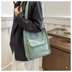 Detailed texture of light green corduroy shoulder bag with front button pocket on model