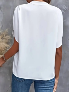 Detail of the back tailoring and draping on white short sleeve blouse for women