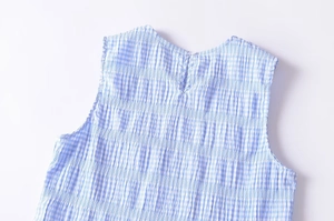 Detail of blue plaid sleeveless top showing pleated texture and back button closure