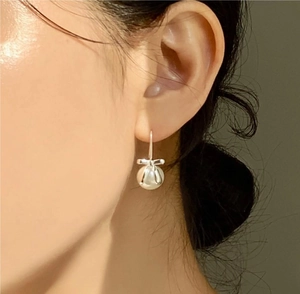 Close-up of elegant 925 silver bow earrings with pearls worn by a model in natural light