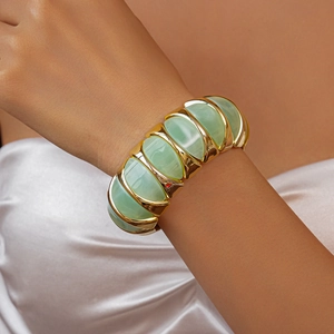 Macro detail of wide acrylic link bracelet featuring mint green segments and gold metal rings
