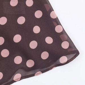 Detail of coffee chiffon fabric with pink polka dots and sheer texture on a halter top