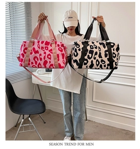Detail shot of large leopard print travel bags in pink and beige with dual handles