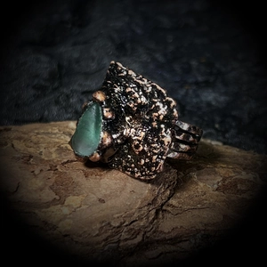 Détail d'une bague ajustable en bronze vintage avec une pierre brute verte sur bois