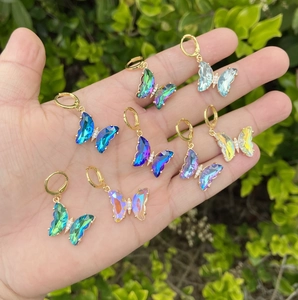 Detailed macro view of vibrant gradient butterfly earrings with 18K gold-plated hoops