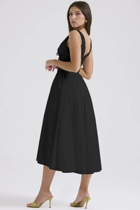 Detail of elegant black V-neck maxi dress with slim fit waist and flowing skirt
