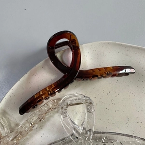 Detail of 13cm amber and clear hair claws with twist design on a ceramic plate