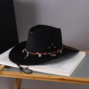 Black western cowboy hat with bohemian shell bead trim on vintage artistic book background