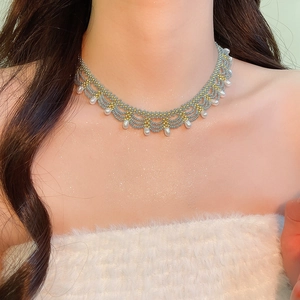 Close-up of hand-woven beaded necklace with grey-blue beads and white teardrop pearls