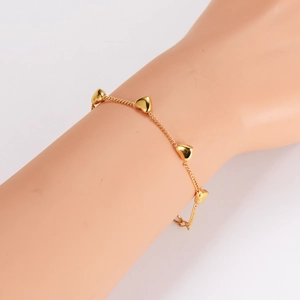 Elegant gold stainless steel bracelet featuring delicate heart pendants on a female wrist