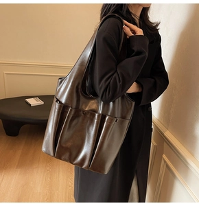 Detail of dark brown vintage leather tote bag with exterior pockets on a model