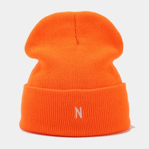 Detailed view of ribbed texture and white letter N embroidery on orange knit beanie
