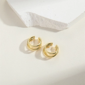 Close-up of golden multi-layer ear cuff earring on textured stone surface background