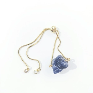 Detail of adjustable gold box chain bracelet with irregular raw blue crystal stone