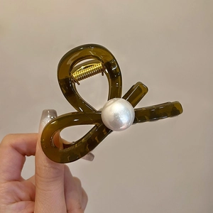Close-up of a brown tortoiseshell hair claw clip with a large pearl and gold spring