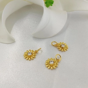 Three 14K gold plated daisy pendants with zircon accents on elegant white silk background