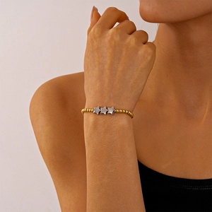 Détail du bracelet à perles avec sphères dorées et breloques étoiles argentées au poignet