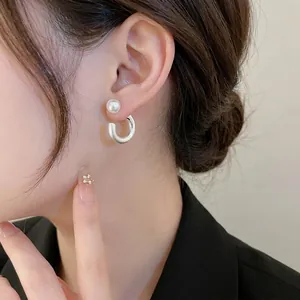Minimalistische Perlen und silberne C-förmige Ohrhänger am Model für einen modernen Fashion-Look