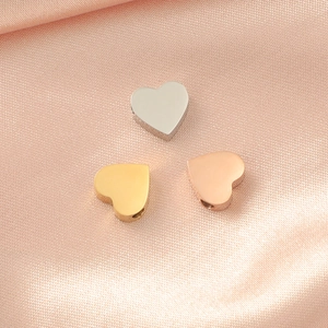 Polished heart shaped charms in silver gold and rose gold finish on pink silk fabric