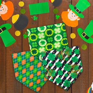 Flat lay of St. Patrick’s Day pet bandanas with clover and plaid patterns on wood