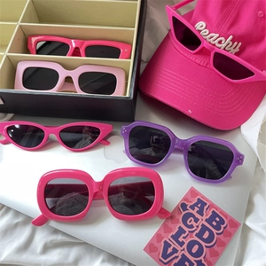 Flat lay of colorful pink and purple thick frame sunglasses with a lifestyle background