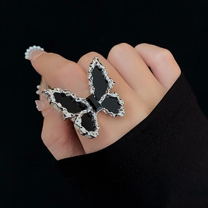 Detailed close-up of a large black butterfly ring on a hand with silver textured borders