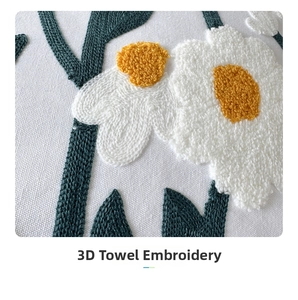 Macro detail of 3D towel embroidery showing white and yellow daisy flowers on fabric