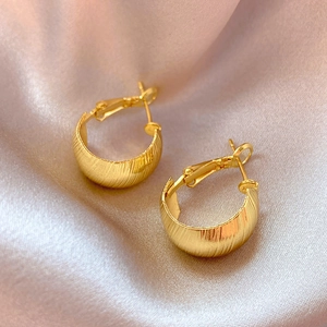Detail view of gold C-shape hoop earrings featuring vertical brushed metal texture
