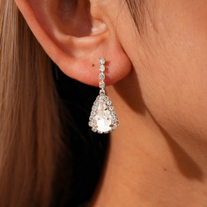 Close-up of silver drop earrings with sparkling rhinestones worn on a model's ear