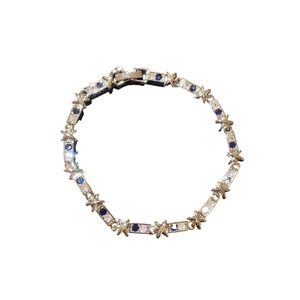 Bracciale X in argento con zirconi scintillanti e pietre blu e bianche su sfondo bianco