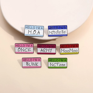 Colorful metal enamel K-Pop fan name badges displayed on a white round base
