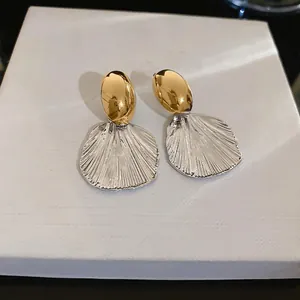 Élégantes boucles d'oreilles ovales bicolores avec pendentifs texturés sur fond blanc