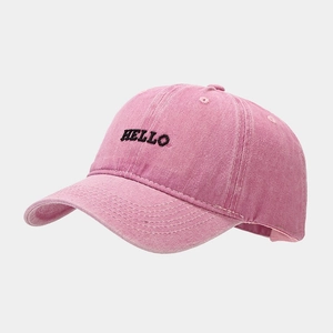 Close-up of pink washed cotton baseball cap featuring black HELLO embroidery details