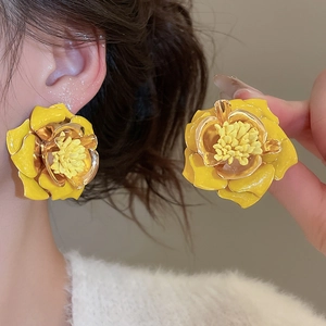 Détail de boucles d'oreilles fleur en émail jaune avec bords dorés et pétales 3D