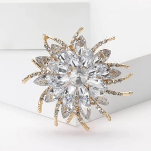 Macro shot of a light gold floral brooch with crystals and rhinestones on a white stand