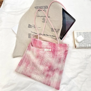 Detailed close-up of pink tie-dye tote bag with lace trim and daily essentials set