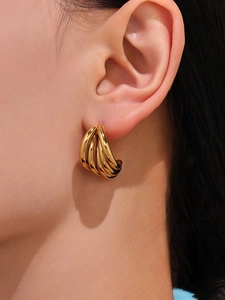 Detail of multilayer C-shaped 18K gold-plated geometric earrings worn by a model