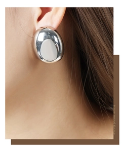 Polished silver bean earring closeup showing glossy mirror finish on female model