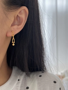 Close-up of golden S925 sterling silver horseshoe ball earrings worn by a model