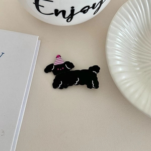 Cute black puppy hair clip with pink birthday hat on beige leather background