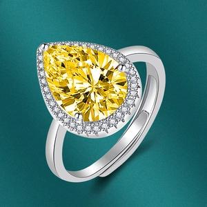 Detailed macro shot of pear-shaped yellow zircon ring with silver claw setting and small crystals