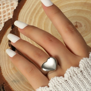 Detailed view of a silver heart-shaped ring with polished finish on a wooden background