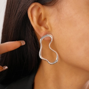 Close-up of minimalist silver irregular fluid earrings worn by a model on the ear