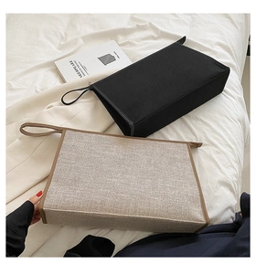 Détail de pochettes business en toile avec fermeture éclair et dragonne sur literie blanche