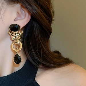 Detail shot of golden leopard head earrings with black stones and teardrop dangle on model