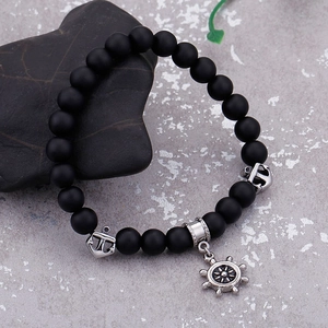 Matte black onyx beads bracelet with silver anchor and helm charms on grey stone