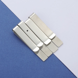 Close-up of four silver brushed stainless steel money clips on a dual-tone blue background