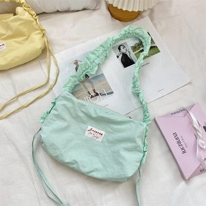 Close-up of pleated mint green nylon bag featuring ruffled edges and a white brand label